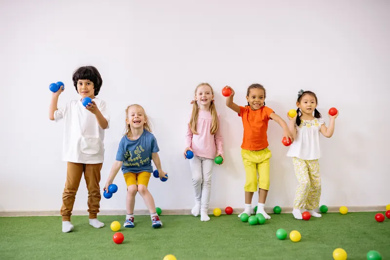 Kinder in weißer Kleidung mit bunten Bällen, Studiofoto