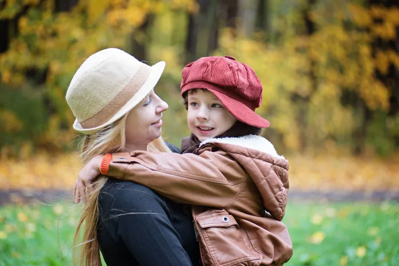 Mutter umarmt ihren Sohn im herbstlichen Park