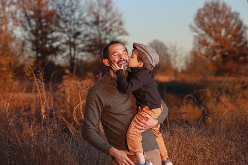 Vater mit Sohn auf dem Arm in herbstlicher Wiese