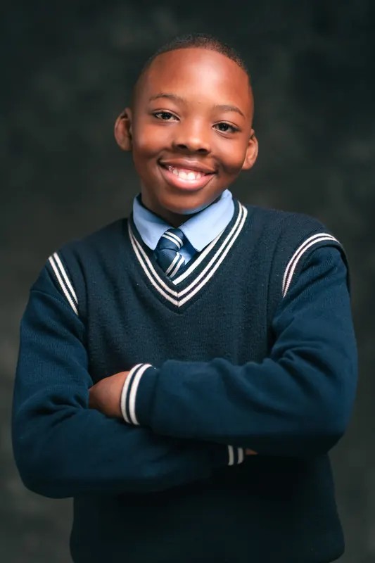 Junge im Schulpullover, Arme verschränkt, Studioporträt