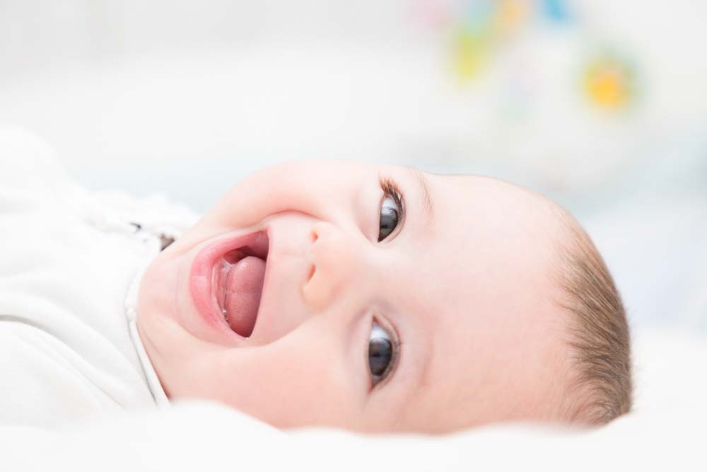 Babyfoto auf dem ein Baby in die Kamera lacht