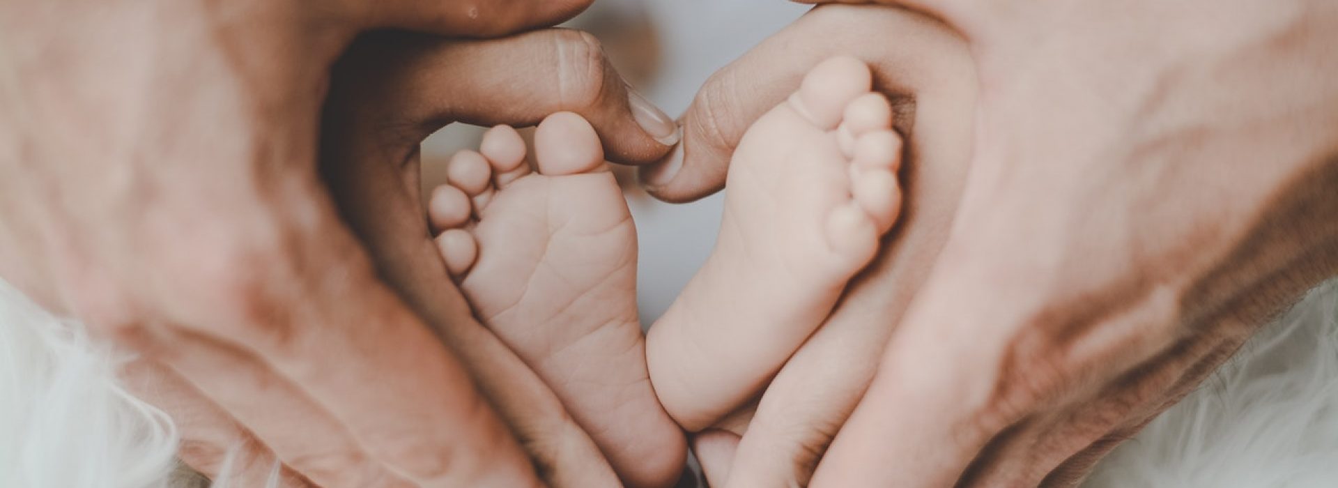 newborn-cover Babyfotoshooting im Studio in Bochum - Eltern halten die Füße ihres Babys