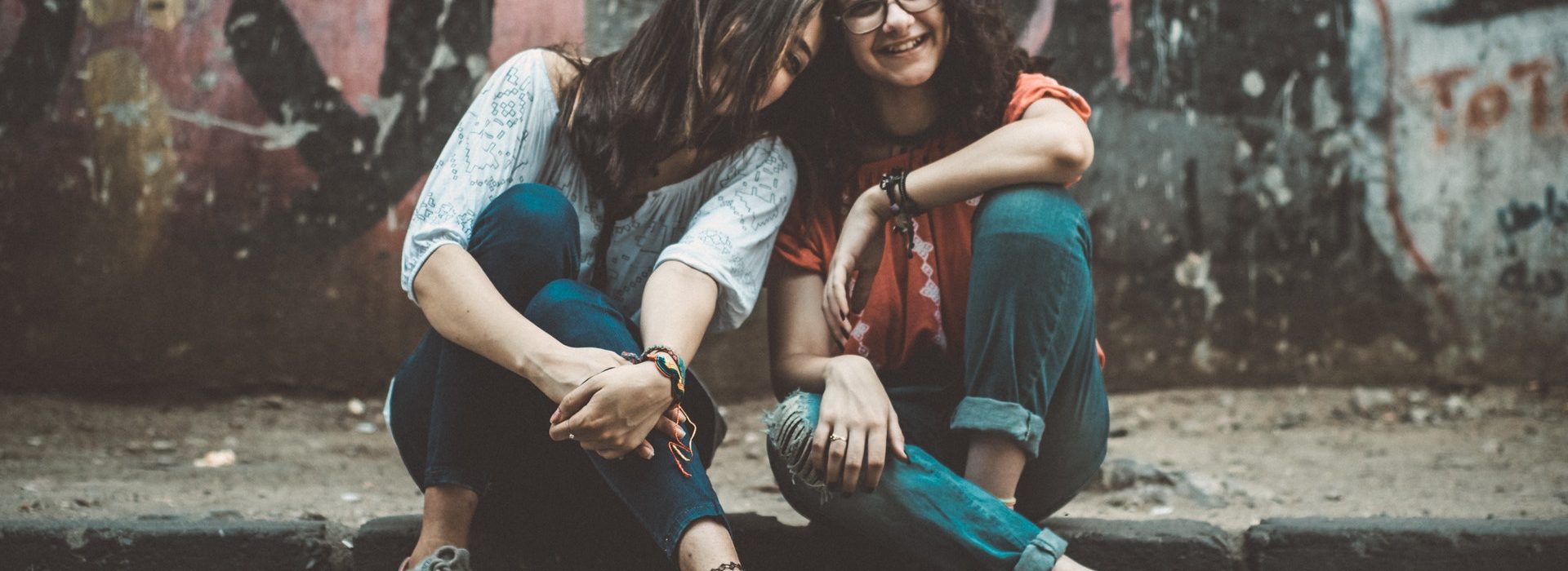 urban-shooting Zwei Frauen sitzen in einer Urban Kulisse vor Graffiti