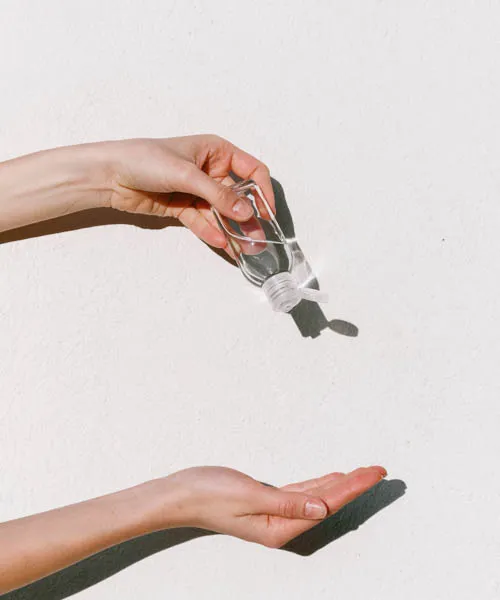 Zwei Hände mit einer Flasche Desinfektionsmittel vor einem Fotograf Hintergrund